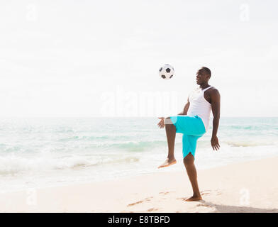 Gemischte Rassen Mann spielt mit Fußball am Strand Stockfoto