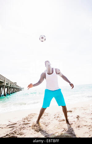 Gemischte Rassen Mann spielt mit Fußball am Strand Stockfoto