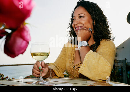 Gemischte Rassen Frau trinkt Wein am Wasser Stockfoto