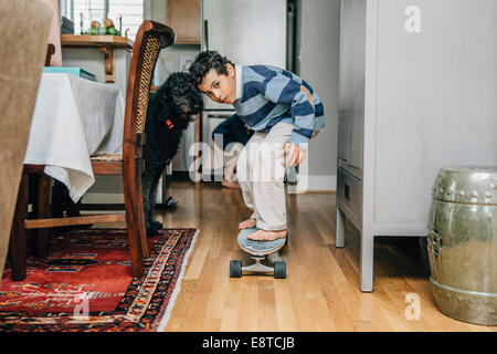 Gemischte Rassen junge fahren Skateboard in Küche Stockfoto