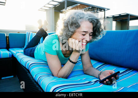 Kaukasische Frau mit Handy auf städtischen Dach Stockfoto