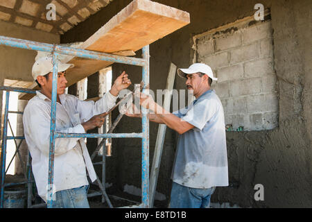 Hispanische Bauarbeiter mit Gerüst auf Baustelle Stockfoto