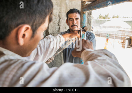 Hispanische Bauarbeiter mit Gerüst auf Baustelle Stockfoto