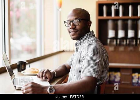 Schwarzer Mann mit Laptop im Café Stockfoto