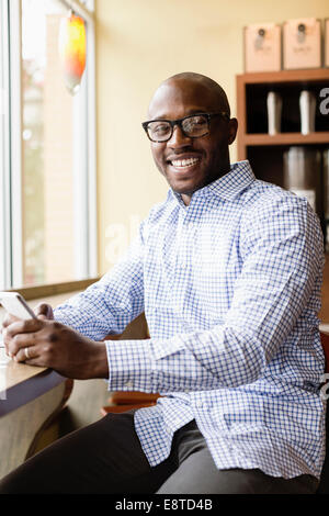 Schwarzer Mann mit Handy in Coffee-shop Stockfoto