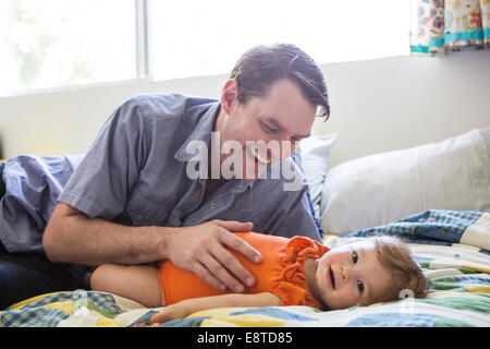 Kaukasische Vater mit Tochter spielen auf Bett Stockfoto