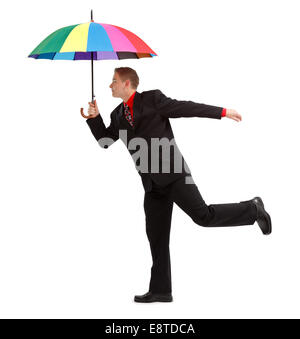 Junger Mann stehend auf einem Bein, mit großen, offenen, bunten Regenschirm Stockfoto
