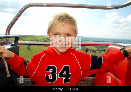 ein junges glücklich lächelnde Kind in einem roten Kapuzenpullover auf einem oben offenen Doppeldecker-Bus und englische Landschaft am Devils Dyke in der Nähe von brighton Stockfoto