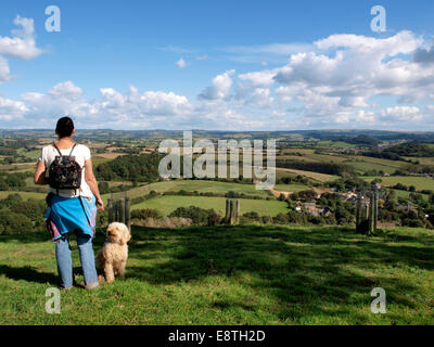 Frau und Hund stehend auf der Oberseite Colmers Hügel mit Blick über die Dorset Landschaft, Symondsbury, Dorset, Großbritannien Stockfoto
