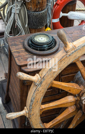 Schiffe-Kompass und Lenkrad auf dem Deck eines alten Windjammer. Stockfoto