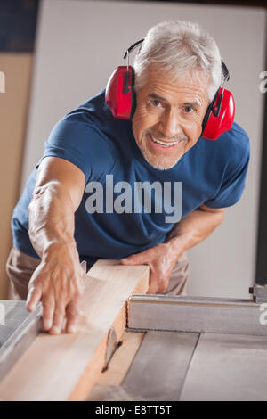 Portrait von Schreiner Schneiden von Holz mit Tablesaw Stockfoto