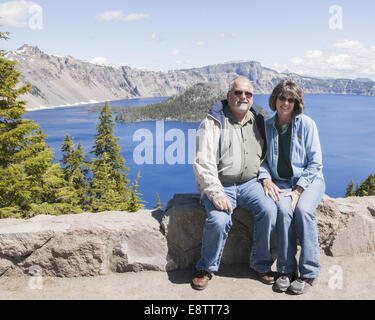 Paar sitzt auf Felsvorsprung am Crater Lake, Oregon Stockfoto