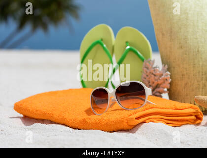 Sommer-Strand-Tasche mit Seestern, Handtuch, Burschen gesungen und Flip-Flops am Sandstrand Stockfoto