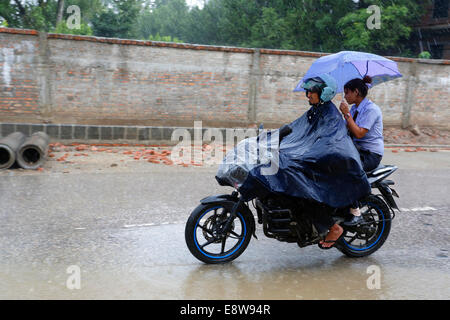 Menschen auf dem Motorrad auf der überfluteten Straße nach Monsun Sturm, Kathmandu, Nepal Stockfoto