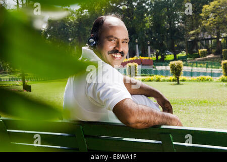 1 indischer Mann hören von Musik im Park Stockfoto