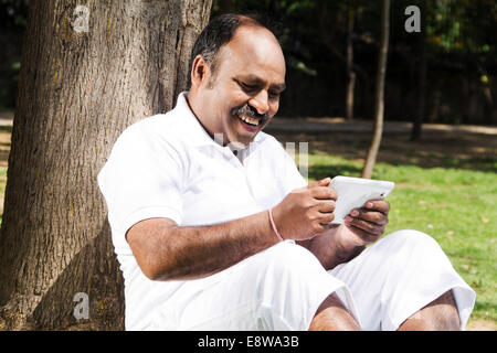 1 indischer Mann sitzen im Park mit mobilen Stockfoto