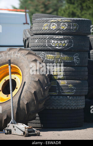 Alte Autoreifen und ein Traktor Rad gestapelt vor eine Garage, eine Kreidezeichnung Cartoon-Charakter erscheint auf den alten Reifen Stockfoto