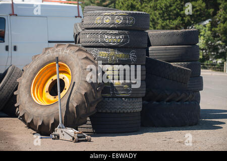 Alte Autoreifen und ein Traktor Rad gestapelt vor eine Garage, eine Kreidezeichnung Cartoon-Charakter erscheint auf den alten Reifen Stockfoto