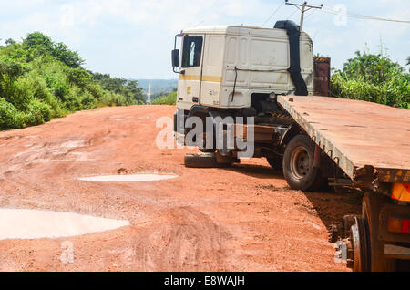 Schlammige Feldwege in Nigeria während der regnerischen Jahreszeit und einem zerstörten Lastwagen mitten auf der Straße Stockfoto