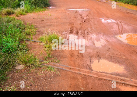 Schlammige Feldwege in Nigeria während der Regenzeit und eine verlassene alte Bahnstrecke die überfluteten Pfützen Stockfoto