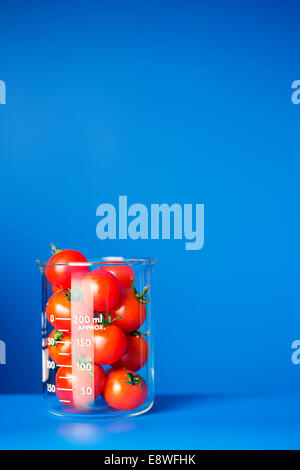 Becher mit kleinen Tomaten auf blauen Schalter Stockfoto