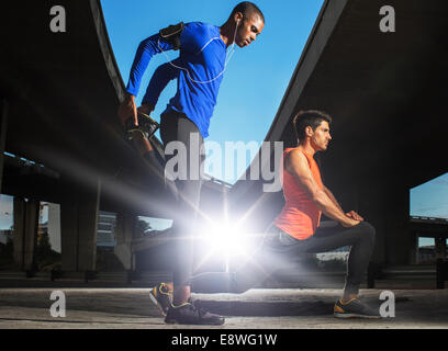 Männer dehnen vor dem Training auf Stadtstraße Stockfoto