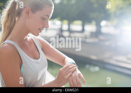 Frau mit Blick auf die Uhr vor dem Training auf Stadtstraße Stockfoto