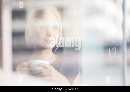 Frau trinkt Kaffee drinnen Stockfoto
