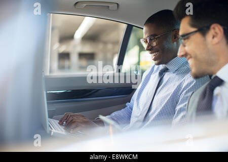 Geschäftsleute, die mit Laptop im Auto Stockfoto