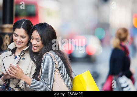 Frauen, die am Handy auf Stadtstraße Stockfoto