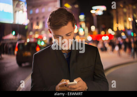 Mann mit Handy auf Stadtstraße in der Nacht Stockfoto