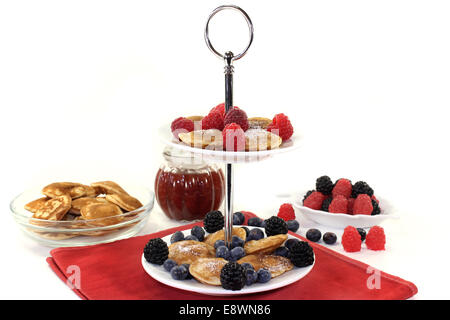 Poffertjes mit Himbeeren und Heidelbeeren auf eine Kuchenplatte Stockfoto