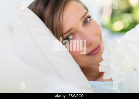 Nahaufnahme von Frau riechende Blume auf Bett Stockfoto