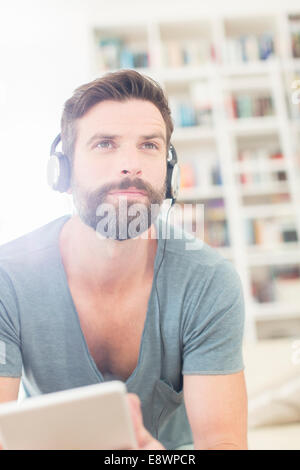 Mann, die Musik im Wohnzimmer hören Stockfoto