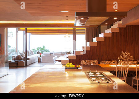 Arbeitsplatte, Treppe und Sofa im offenen modernen Küche und Wohnbereich Stockfoto