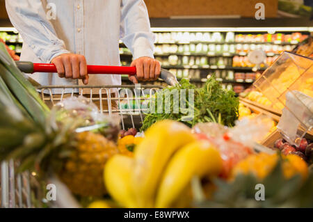 Der Mann schob vollen Einkaufswagen im Supermarkt hautnah Stockfoto