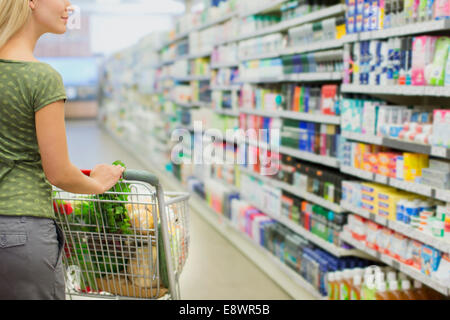 Frau schob vollen Einkaufswagen im Supermarkt Stockfoto