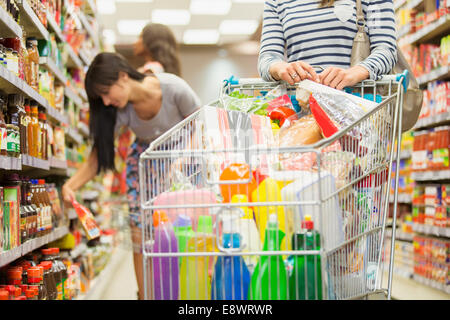 Frau schob vollen Einkaufswagen im Supermarkt Stockfoto