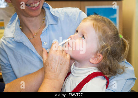 2 Jahre altes Kind mit ihrer Mutter / Mutter, erhält Dosis der Fluenz Grippe-Impfstoff Nasenspray Immunisierung von NHS Practice Nurse UK Stockfoto