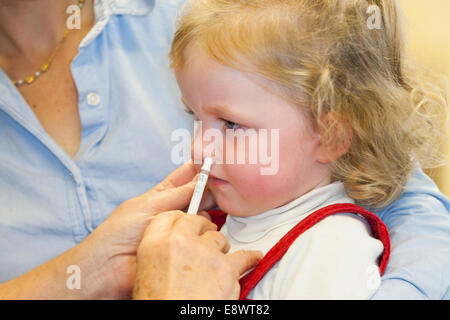 2 Jahre altes Kind mit ihrer Mutter / Mutter, erhält Dosis der Fluenz Grippe-Impfstoff Nasenspray Immunisierung von NHS Practice Nurse UK Stockfoto