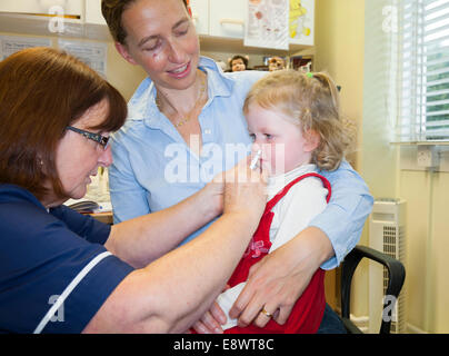 2 Jahre altes Kind mit ihrer Mutter / Mutter, erhält Dosis der Fluenz Grippe-Impfstoff Nasenspray Immunisierung von NHS Practice Nurse UK Stockfoto