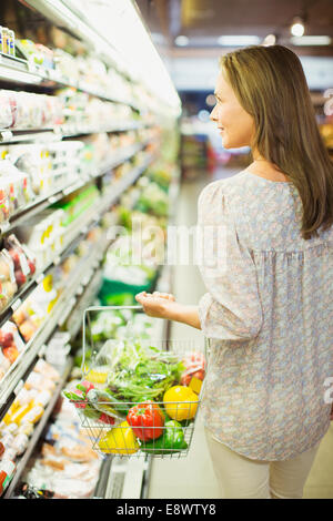 Frau mit vollen Einkaufswagen im Supermarkt Stockfoto