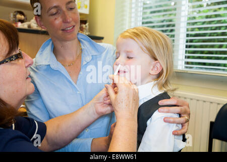 4 Jahre altes Kind mit ihrer Mutter / Mutter, erhält Dosis der Fluenz Grippe-Impfstoff Nasenspray Immunisierung von NHS Practice Nurse UK Stockfoto