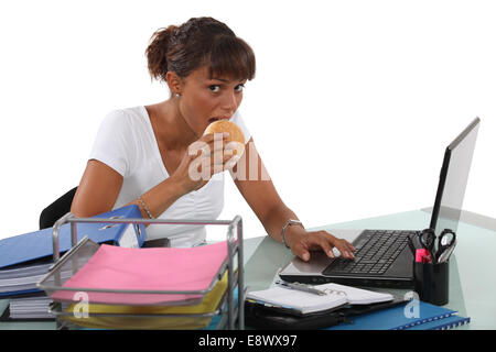 Frau Essen Sandwich am Schreibtisch Stockfoto