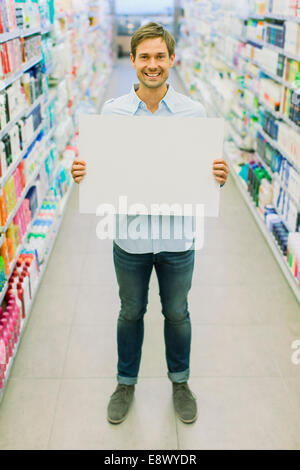 Mann, der leere Karte im Lebensmittelgeschäft Gang hält Stockfoto