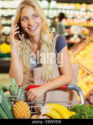Frau am Handy während des Einkaufs im Supermarkt Stockfoto