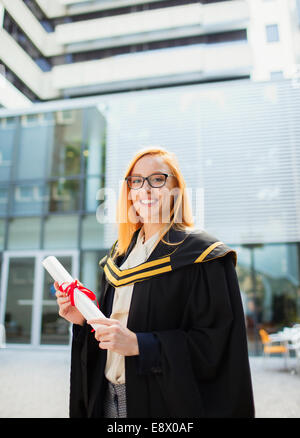 Student in Mütze und Mantel hält Schriftrolle Stockfoto