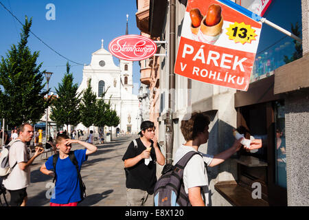 Tschechische Teens Hot Dogs in Joštova Straße mit Thomaskirche im Hintergrund zu kaufen. Brno, Tschechische Republik Stockfoto