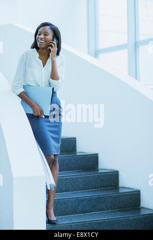 Geschäftsfrau, die zu Fuß auf Handy auf Treppe Bürogebäude Stockfoto