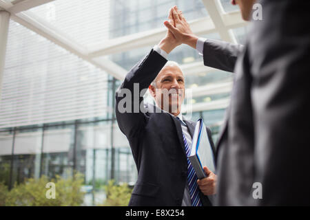 Geschäftsleute hohe Fiving außerhalb Bürogebäude Stockfoto